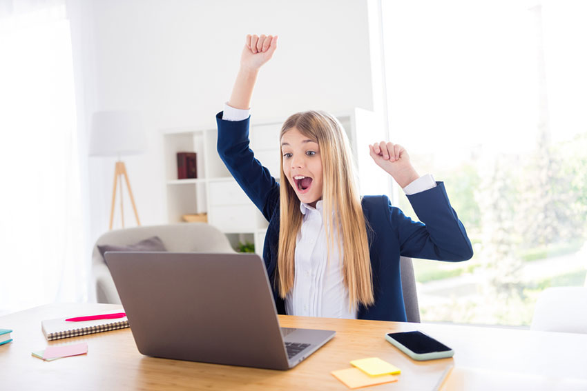 student celebrating in front of laptop