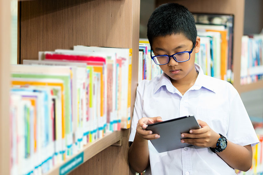 student looking at tablet in library